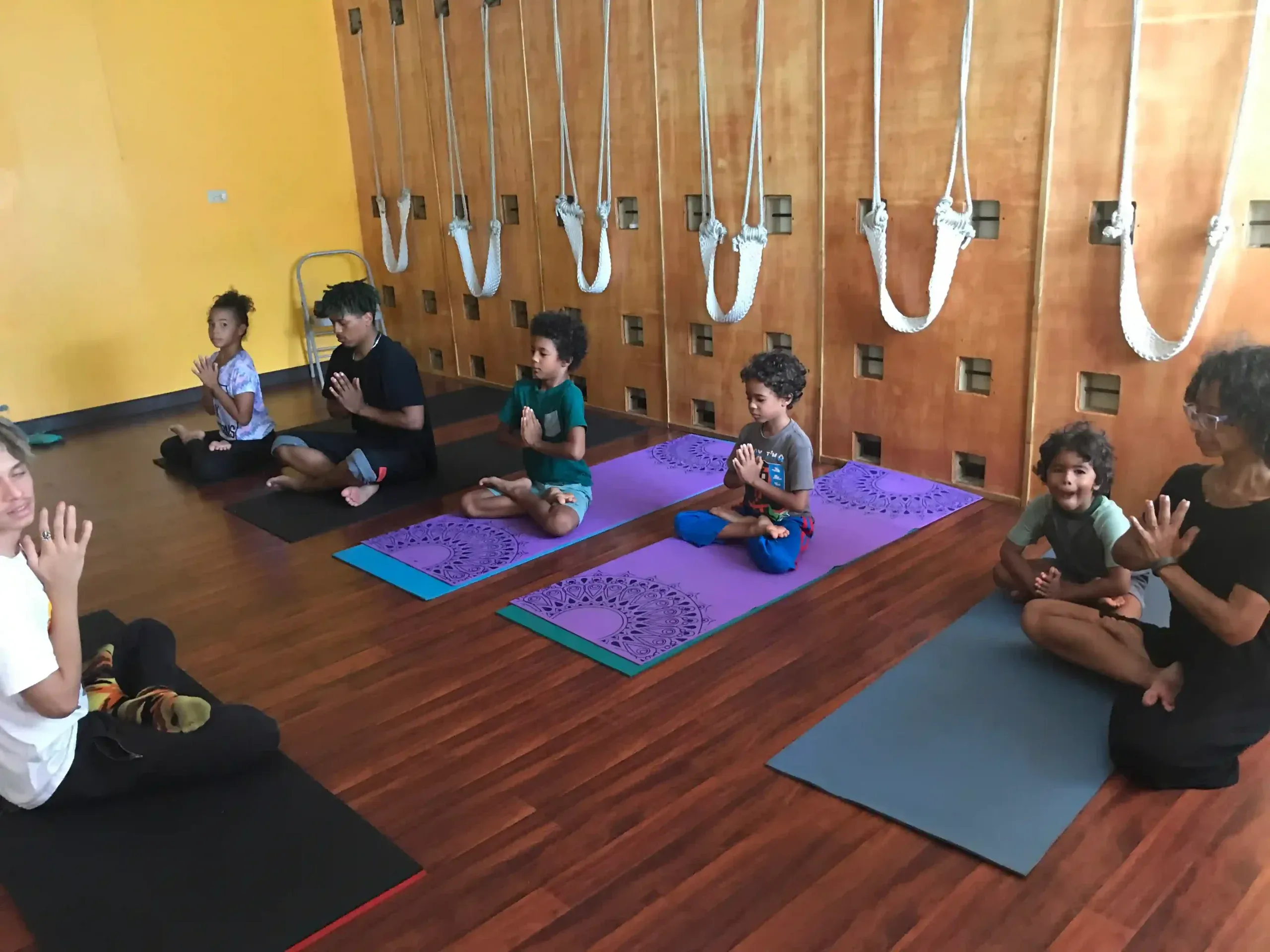 A teacher guiding a class of children seated on their mats