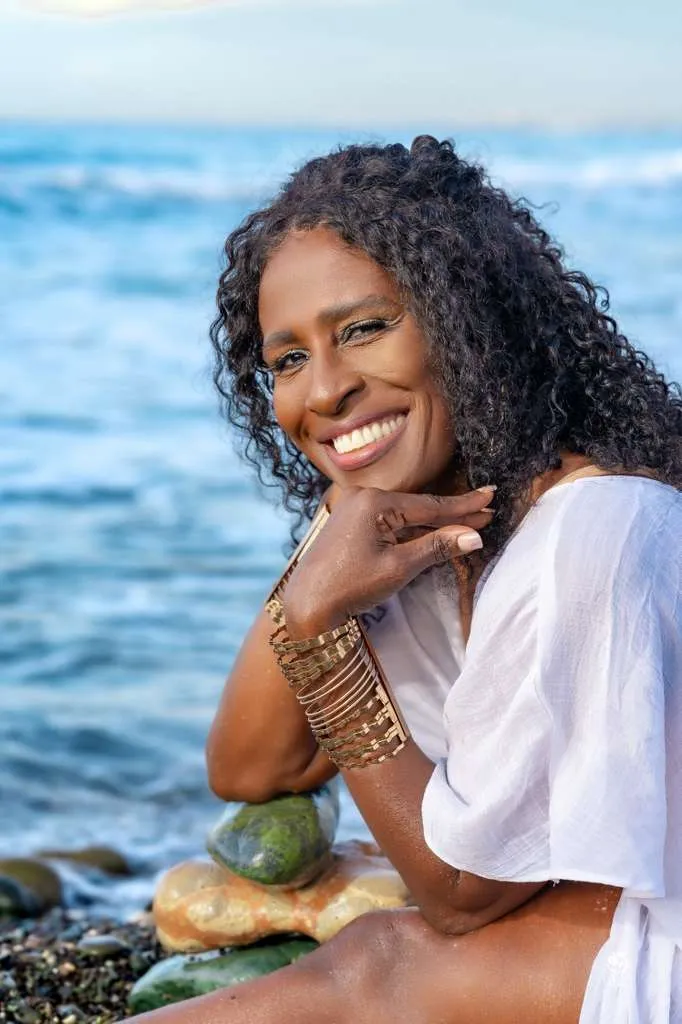 Subhadra (Sandra Griffiths), founder of Yoga Angels International, smiling by the sea in Jamaica