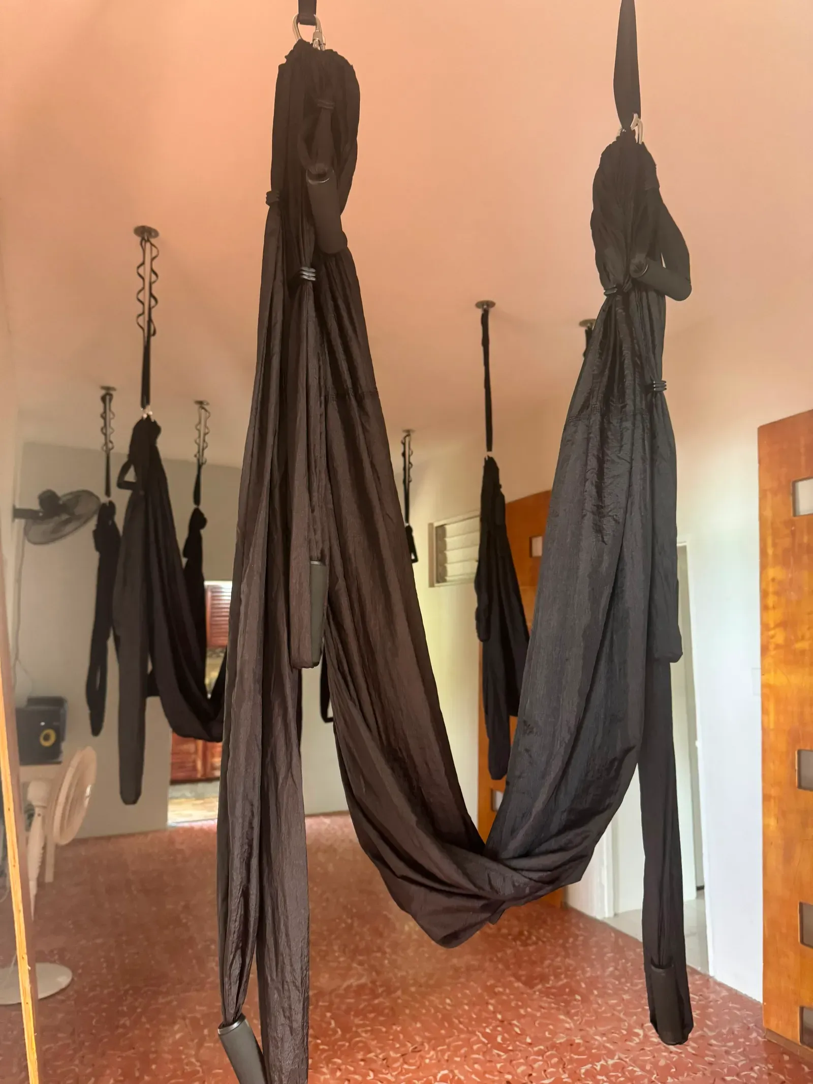Soft fabric aerial yoga hammocks hanging from the ceiling in the studio at the YAI Wellness Oasis in St. Thomas, Jamaica